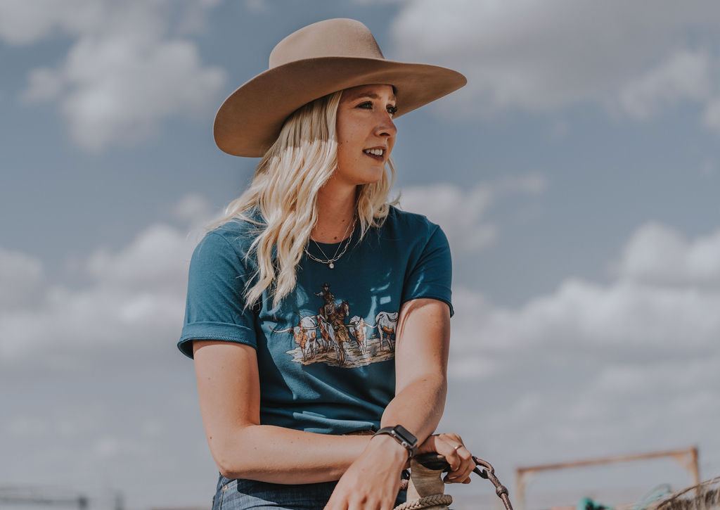 Cowgirl on horse wearing cattle drive tee