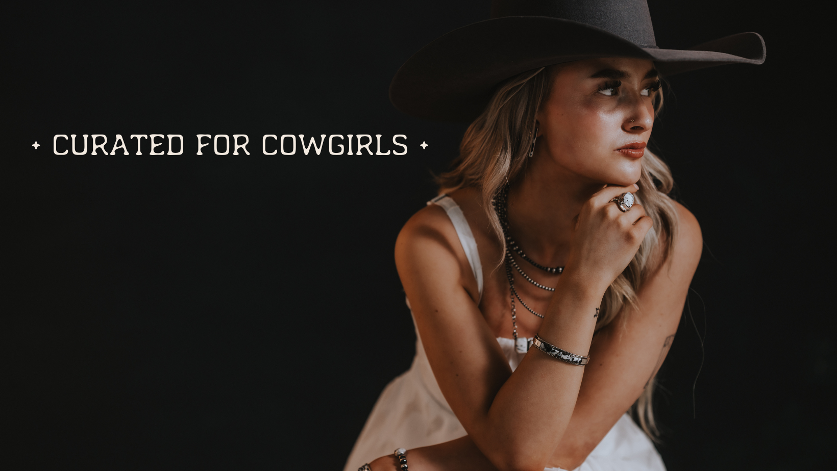 Woman wearing a cowboy hat and turquoise jewelry with text 'Curated for Cowgirls' on a dark background